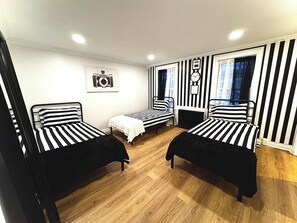 Una habitació amb tres llits, un rellotge a la paret i una càmera penjada a la paret.