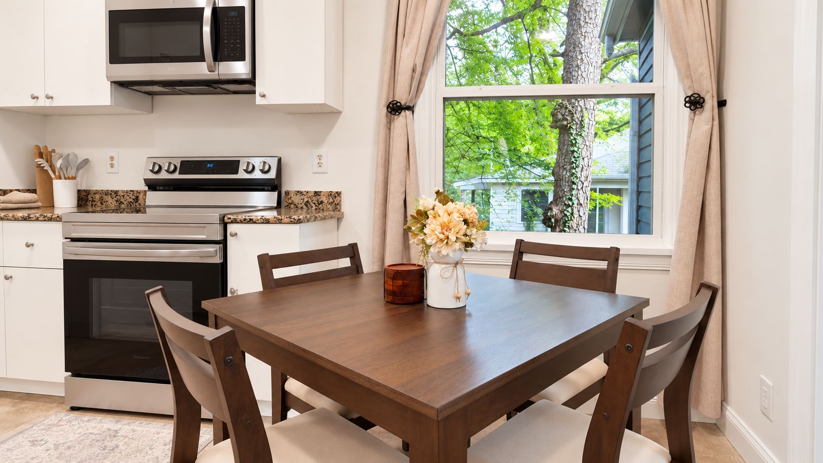 A kitchen with a microwave, oven, and stove, a dining table with chairs, and a window with curtains.