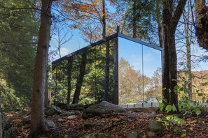 Une structure moderne en verre, située dans une zone boisée et entourée d’un environnement naturel.