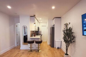 Una cucina moderna con isola centrale, pavimento in legno e illuminazione a sospensione.