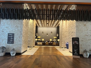 Un vestíbulo de hotel con mostrador de recepción, piso de madera y jarrones decorativos.