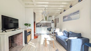 A modern living room with a television, sofa, and a fireplace. - Le Temps des Violettes - 3-Bedroom Apartment in the Heart of Downtown with a View of the Harbor Towers (Trouville-sur-Mer)