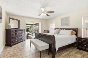 A bedroom with a bed, a dresser, a bench, a ceiling fan, and a view of the outdoors. - 3-bedroom house in Seminole with lanai and temperature controlled pool. (Seminole)