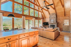 A spacious living area with a stone fireplace, wooden ceiling beams, and large windows. - Afton View Lodge (Afton)