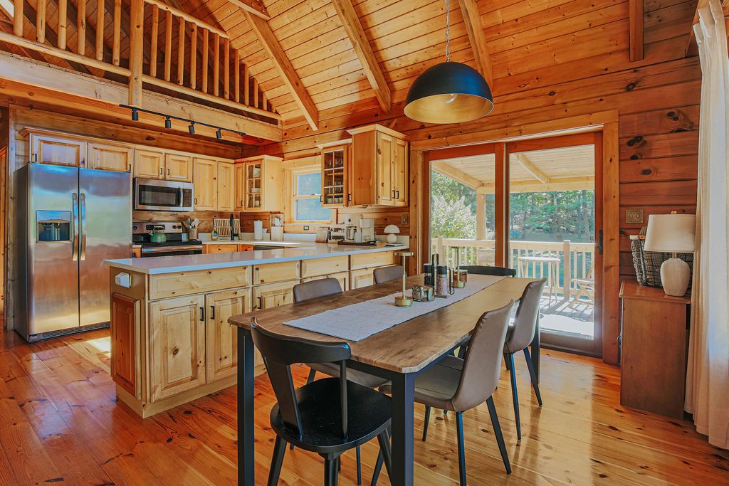 L’intérieur d’un chalet en bois comprend une cuisine, un coin repas et de grandes fenêtres.