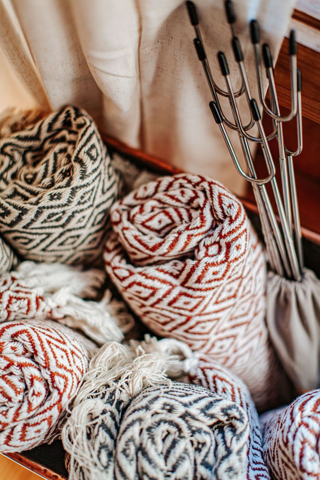 A collection of yarn balls in various colors and patterns, with knitting needles in the background.