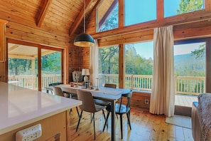 A wooden cabin interior with a dining area, large windows, and a view of the outdoors. - Afton View Lodge (Afton)