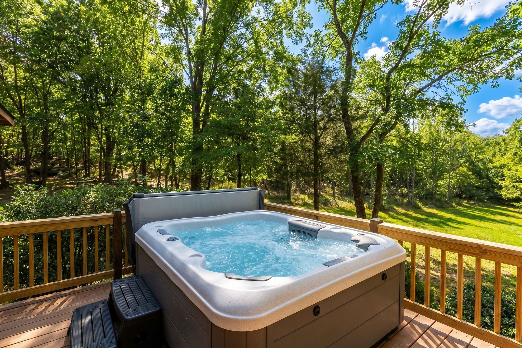 Un bain à remous sur une terrasse en bois, avec vue sur une zone boisée.