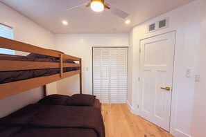 Una habitación con literas, una puerta y un ventilador de techo.