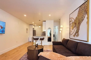 Ein modernes Wohnzimmer mit einem braunen Sofa, einem runden Couchtisch und einem Leopardenmuster-Kunstwerk an der Wand.