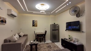 A modern living room with a sofa, dining table, and a flat-screen TV mounted on the wall. - Tremendous 2-bedroom apartment with AC in Red Sea, Hurghada (Red Sea Governorate)