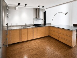 Une cuisine moderne avec des meubles en bois, une hotte en acier inoxydable et un plan de travail noir.