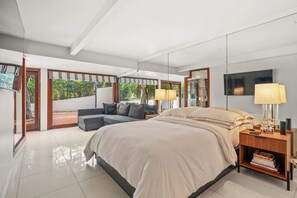 A modern bedroom with a large bed, a sofa, and a desk with a lamp. - Casa Seraphina by Oraklus (Los Angeles)
