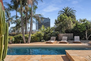 A pool with lounge chairs, palm trees, and a building in the background. - Casa Seraphina by Oraklus (Los Angeles)
