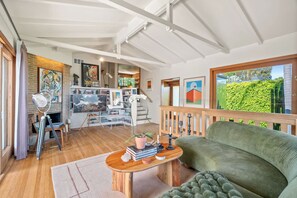 A spacious living area with a green sofa, wooden coffee table, and a fireplace. - Casa Seraphina by Oraklus (Los Angeles)