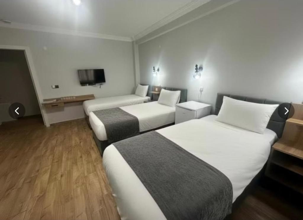 A hotel room with two beds, a flat-screen TV, bedside lamps, and a wooden floor.