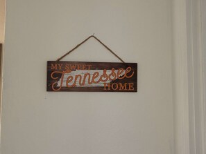 Ein hölzernes Schild mit der Aufschrift 'MY SWEET Tennessee HOME' hängt an einer Wand.