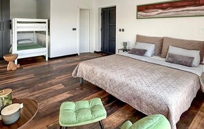 A bedroom with a large bed, a small stool, a wooden floor, and a door. - Gorgeous home in Nova Diklenica (Nova Diklenica)