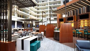A multi-level hotel lobby with seating areas, a bar, and a TV screen. - Elegant Georgetown Retreat | Hilton 1BR Suite | Walk to Shops & Dining (Washington)
