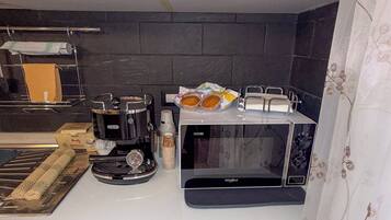 Une cuisine équipée d’une machine à café, d’un grille-pain, d’un four à micro-ondes et d’un égouttoir à vaisselle.