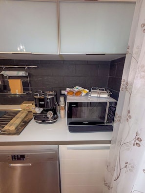 Eine Küche mit Kaffeemaschine, Toaster, Mikrowelle und Geschirrgestell.