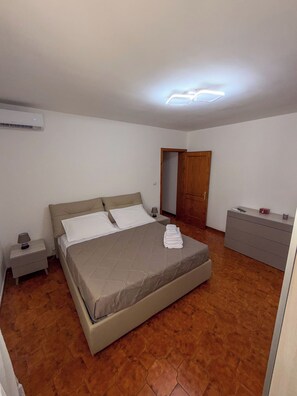 Een slaapkamer met een bed, nachtkastje, dressoir en een airconditioning.
