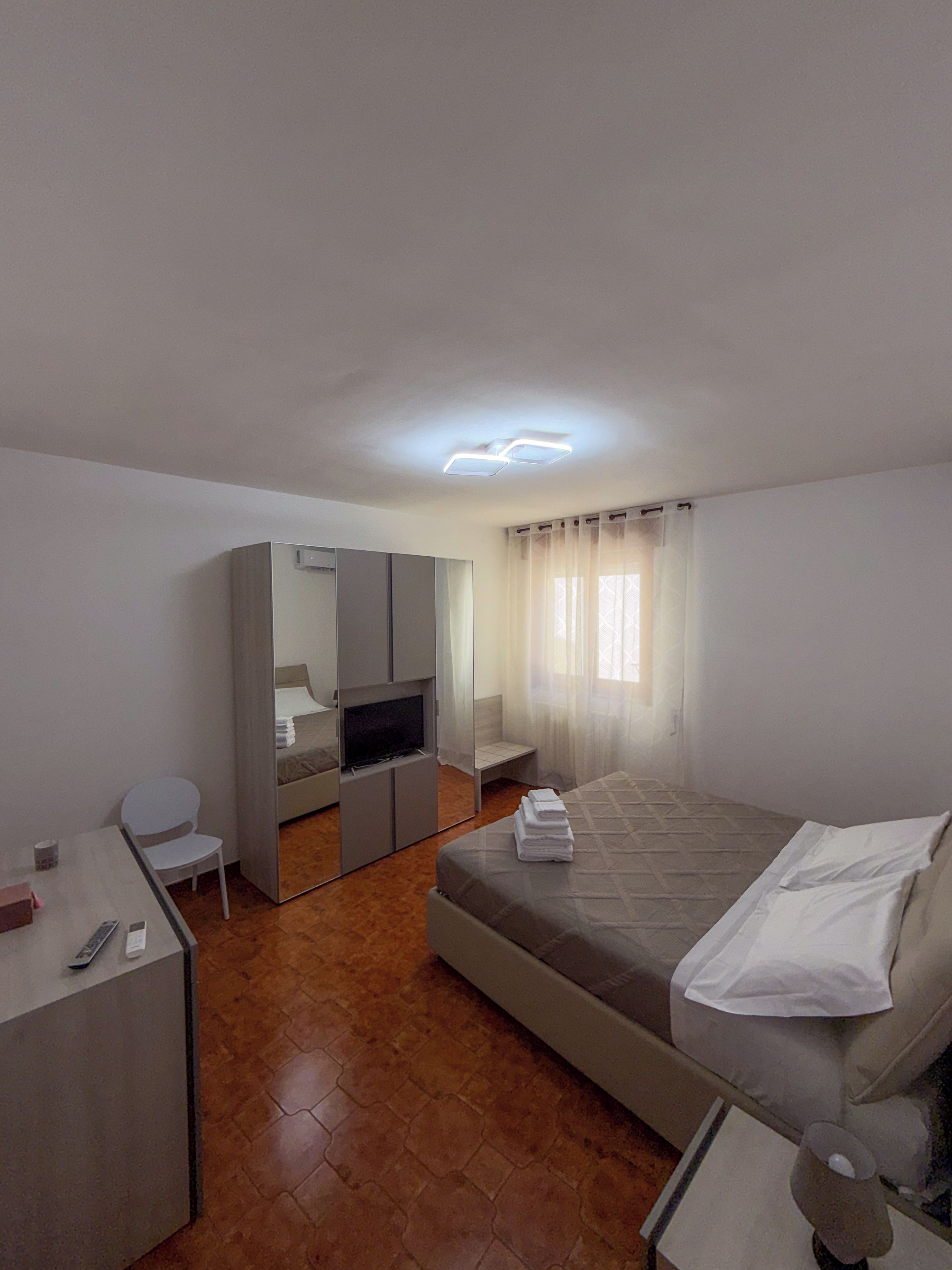 Une chambre d’hôtel avec un lit, un bureau, une télévision et un miroir.