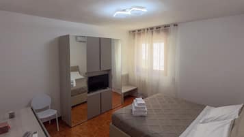 Une chambre d’hôtel avec un lit, un bureau, une télévision et un miroir.