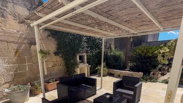 Un espace extérieur aménagé en terrasse, avec une pergola, des meubles en osier et des plantes en pot.