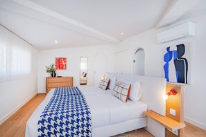 Ein modernes Schlafzimmer mit einem großen Bett, Nachttischen, einer Kommode und Kunstwerken an den Wänden.