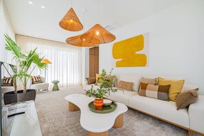 A modern living room with a white sofa, a coffee table, and a large abstract yellow artwork on the wall. - Villa Nostra w/ Pool, Gym & Tennis Court (Albufeira)