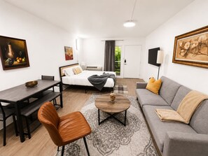 Une chambre d’hôtel moderne équipée d’un lit, d’un canapé, d’une table à manger et d’une petite table basse.
