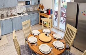 A modern kitchen with a dining table set for six, equipped with a gas stove, microwave, and coffee maker. - Awesome home in Seline with WiFi (Seline)
