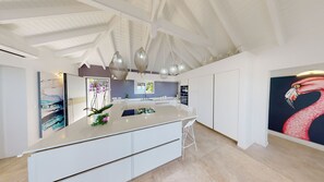 A modern kitchen with a central island, pendant lighting, and a large window. - Vrbo Property (SAINT-MARTIN)