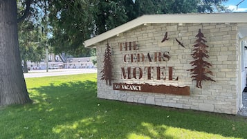 A motel sign with a tree silhouette and the words 'The Cedars Motel' and 'No Vacancy'.