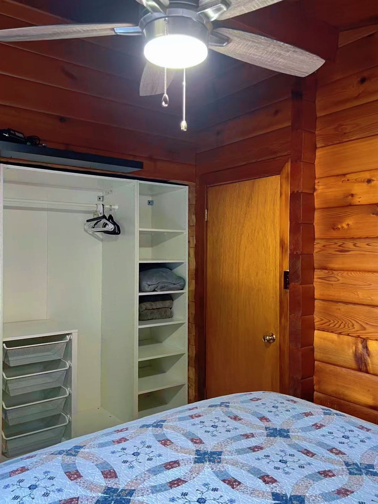 A bedroom with a bed, a wardrobe, and a ceiling fan.