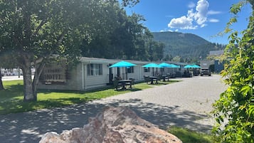 Un motel con mobiliario exterior y montañas al fondo.