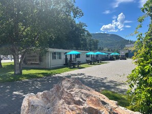 Un motel con mobiliario exterior y montañas al fondo.