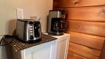 A kitchenette with a toaster, a coffee maker, and a woven mat on the countertop.