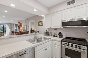 A modern kitchen with white cabinetry, stainless steel appliances, and a dishwasher. - Corner Condo Retreat | 1st Floor | Walk-Out Patio | Optional Saddlebrook Resort Amenities (Wesley Chapel)