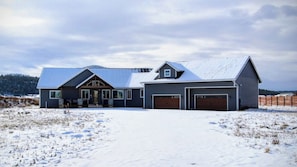 A two-story house with a garage, a covered porch, and a snow-covered landscape. - Flagstaff Family Home with Playroom & Snowbowl (Flagstaff)