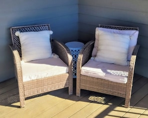 Two wicker chairs with cushions, a small round table, and a blue wall.
