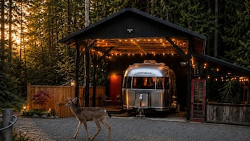 A rustic cabin with a covered area and a trailer parked outside.
