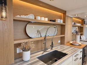 Eine moderne Küche mit integriertem Spülbecken, Holzböden und einem dekorativen Spiegel.