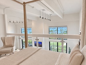 Ein Schlafzimmer mit einem großen Bett, einem Sessel und einem Balkon mit Meerblick.