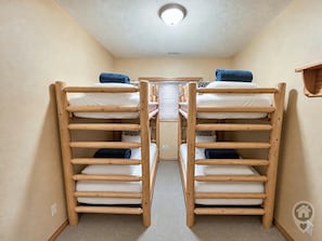 A room with bunk beds, a ceiling light, and a small wooden shelf. - Ski-In/Ski-Out / Private Hot Tub & Mountain Views (Kimberley)