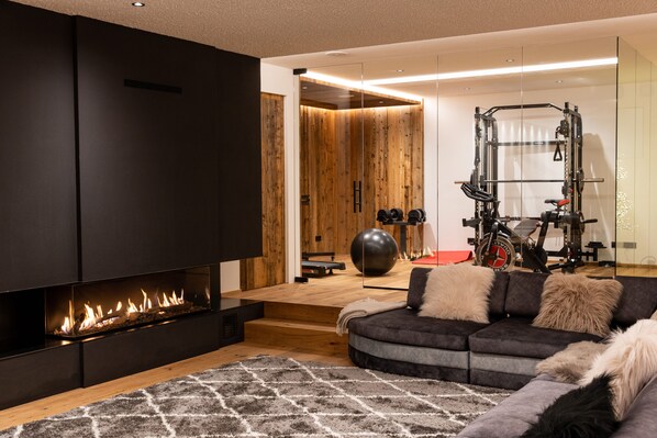 Una sala de estar moderna con chimenea, un sofá, una alfombra y equipo de ejercicios.