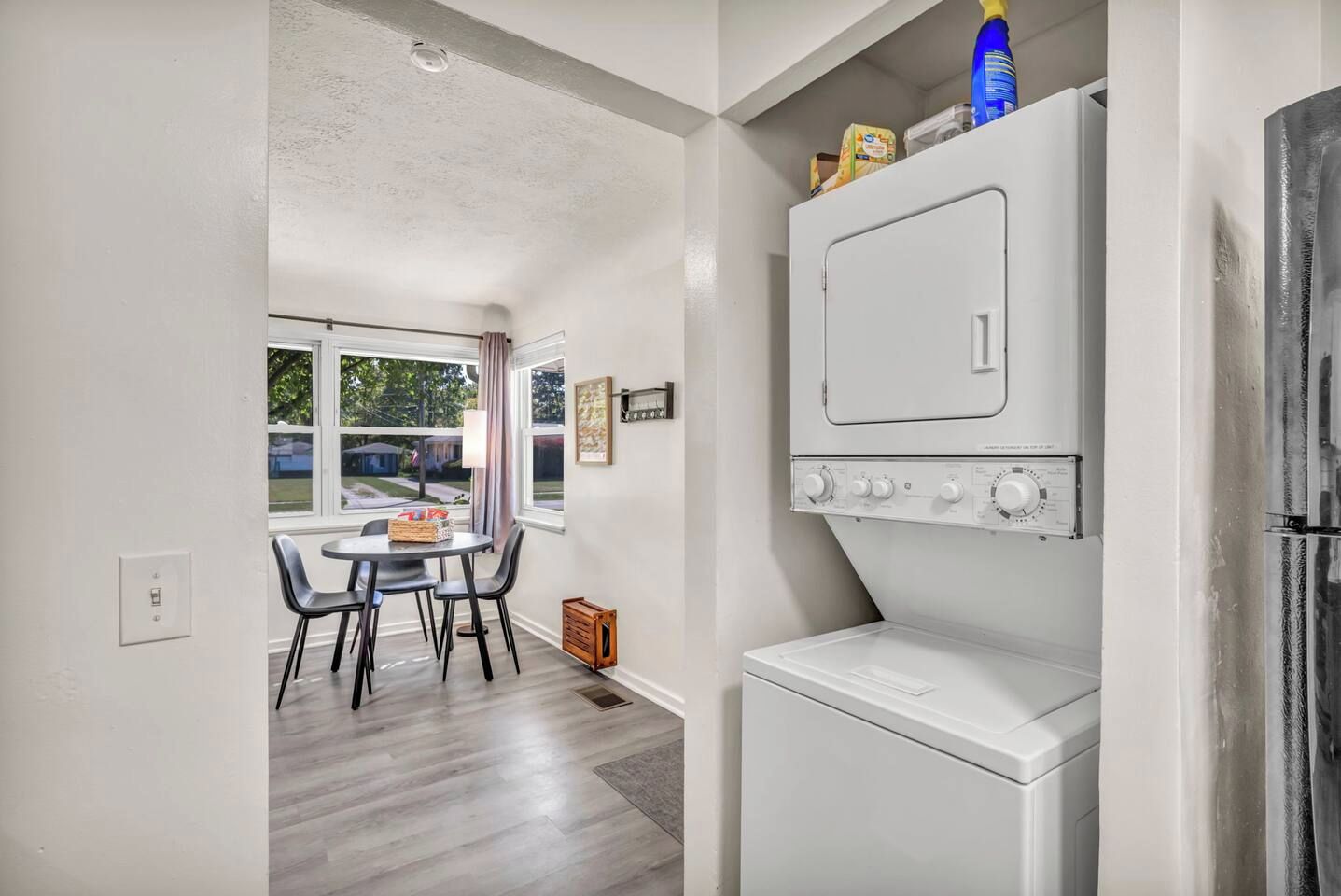 A laundry room with a washer and dryer, a table with chairs, and a window with a view of the outside.