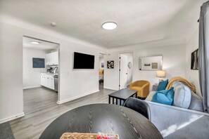 Een moderne woonkamer met een bank, een salontafel en een aan de muur bevestigde televisie.
