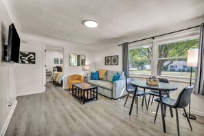 Een moderne woonkamer met een bank, fauteuil, eettafel en stoelen.